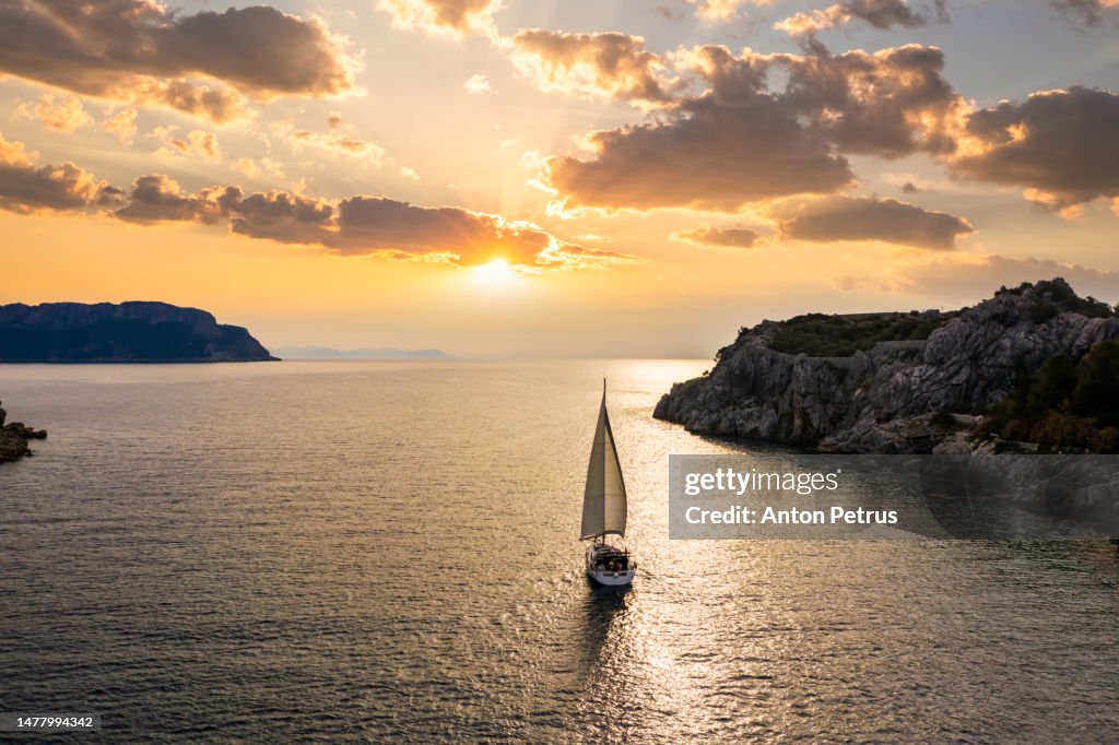 Yacht with sails at sunset near the rocky shore. Turkey