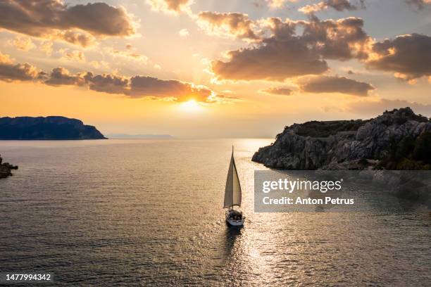 yacht with sails at sunset near the rocky shore. turkey - セーリング ストックフォトと画像