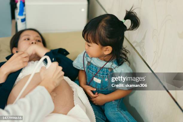 asian baby girl enjoy and was happy to see doctor used an ultrasound sonogram  monitor for  the fetus 34 weeks her mother pregnant - human uterus stockfoto's en -beelden