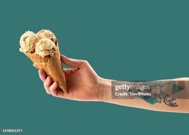 scoop of caramel and nut ice cream in homemade waffle ice cream cone in hand on green background - pistachio ice cream stock pictures, royalty-free photos & images