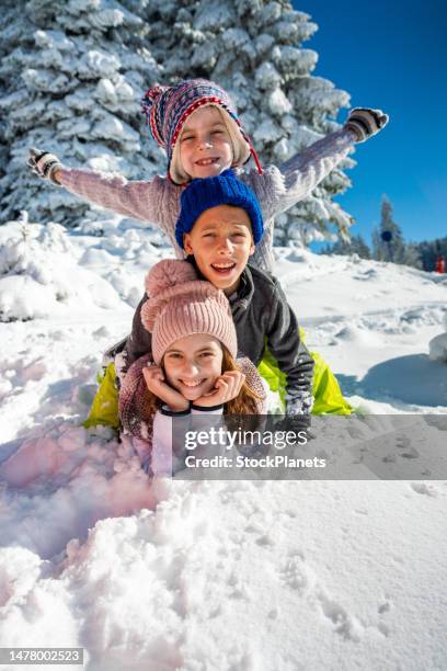 portrait of three little skier lying on snow - kids playing in snow imagens e fotografias de stock