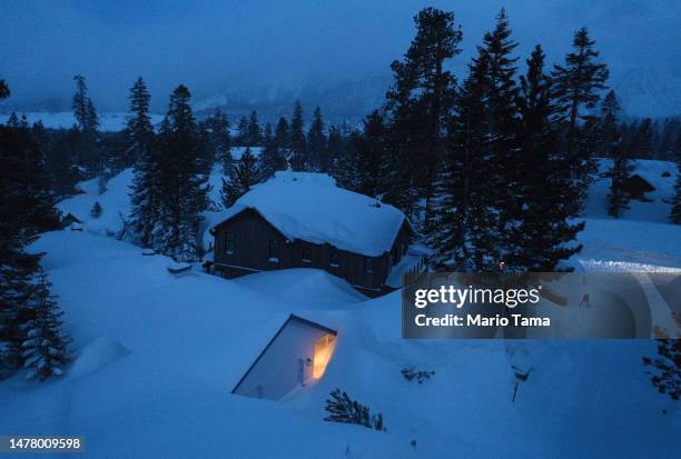 In an aerial view, a person shovels snow in the Sierra Nevada mountains, amid snow piled up from new and past storms, after yet another storm system...