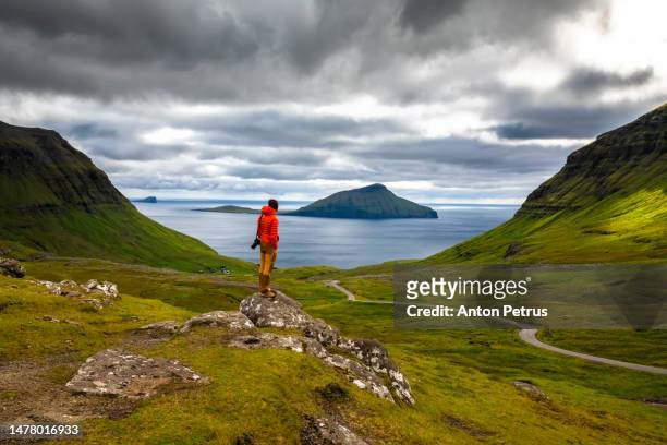 man in front of a mountain landscape in the faroe islands - faroe islands stock pictures, royalty-free photos & images