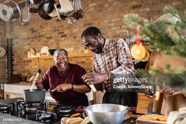 älteres paar scherzt miteinander, während sie zusammen kochen - old person kitchen food stock-fotos und bilder