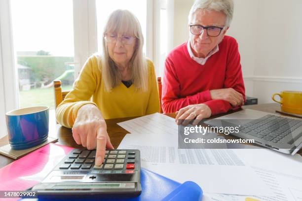 pareja mayor revisando documentos financieros en casa - pensión documento bancario fotografías e imágenes de stock