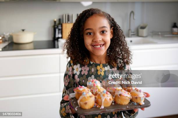 portrait of a smiling young girl with a tray of freshly decorated cakes - kuchen dekorieren stock-fotos und bilder
