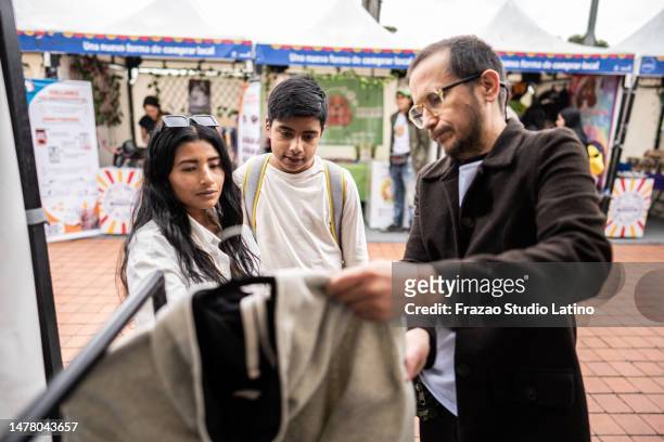 mother and son buying clothes on a market stall - tent sale stock pictures, royalty-free photos & images