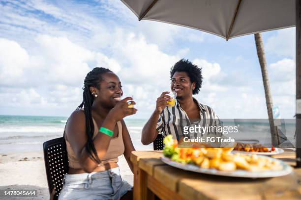 mid adult couple having drinks in a restaurant at the beach - caipirinha stock pictures, royalty-free photos & images