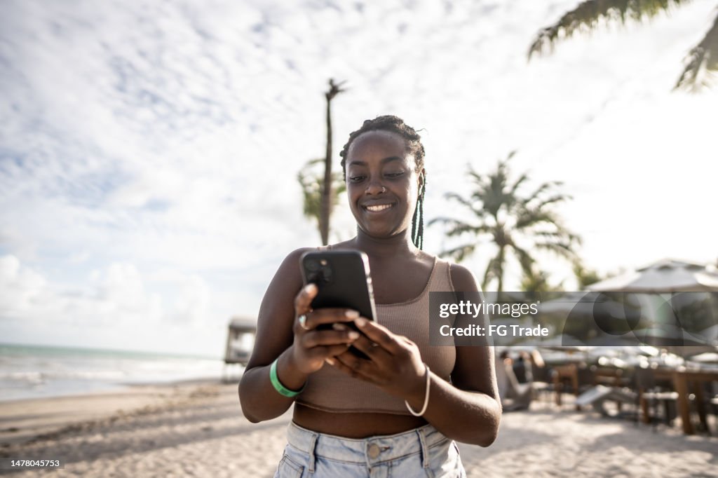 Mulher adulta usando o smartphone na praia