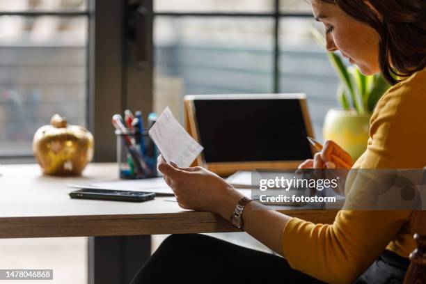 giovane donna che ordina le sue bollette e le sue finanze alla scrivania dell'ufficio a casa - modulo per la dichiarazione dei redditi foto e immagini stock