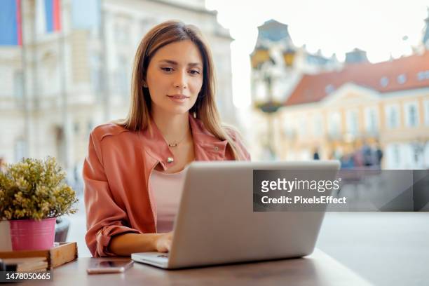 mujer usando una computadora portátil en un café - casualty fotografías e imágenes de stock