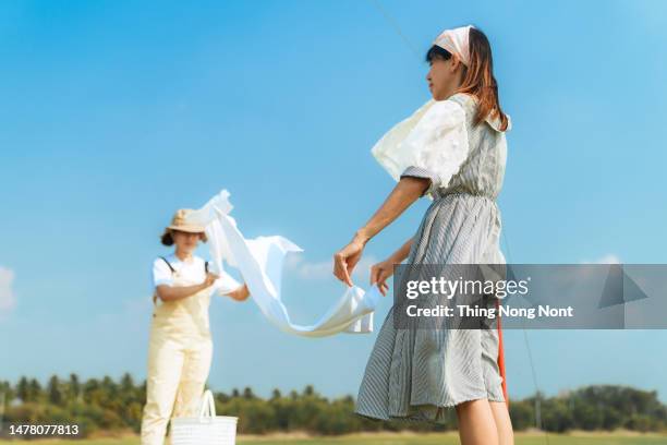 smiling woman friend hangs laundry in the garden. - hanging blouse stock pictures, royalty-free photos & images