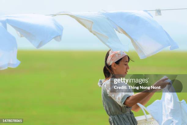 happy woman hangs laundry in the garden - hanging blouse stock pictures, royalty-free photos & images