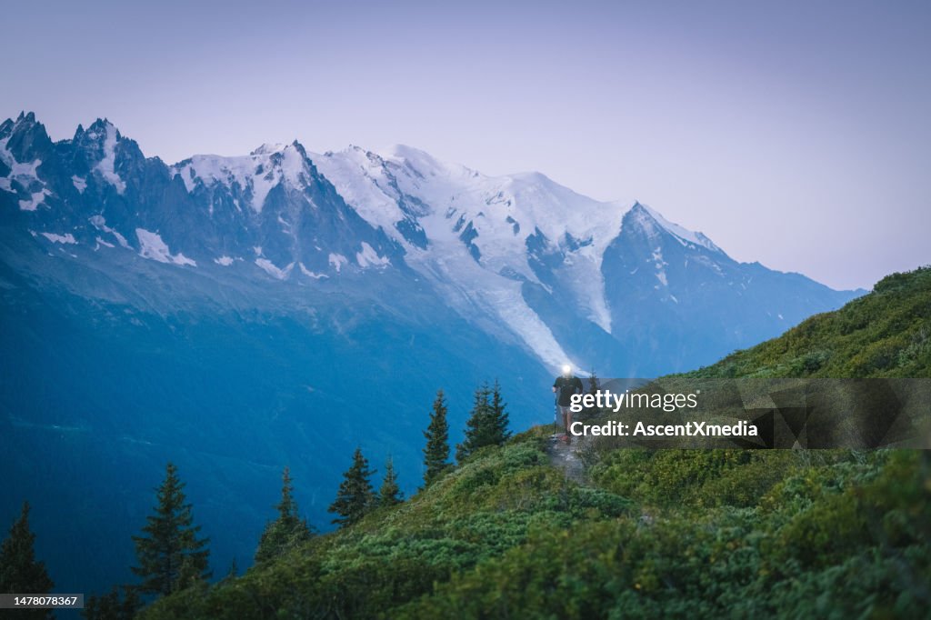 Trail runners bound along mountain trail with headlamp