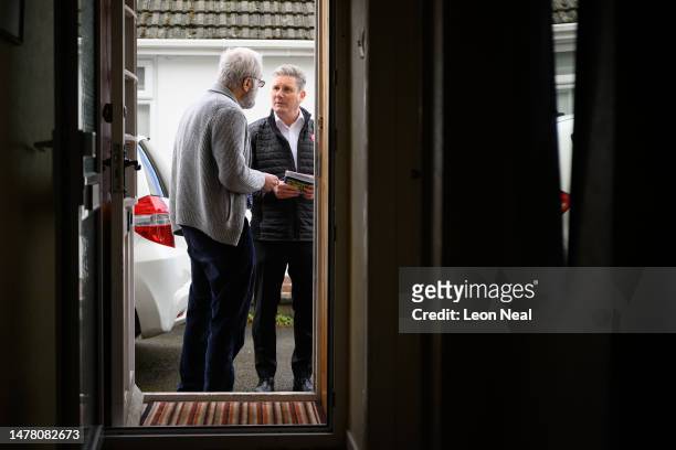 Labour Party leader Keir Starmer speaks with a resident as he delivers leaflets following the launch of Labour's Local Election campaign on March 30,...
