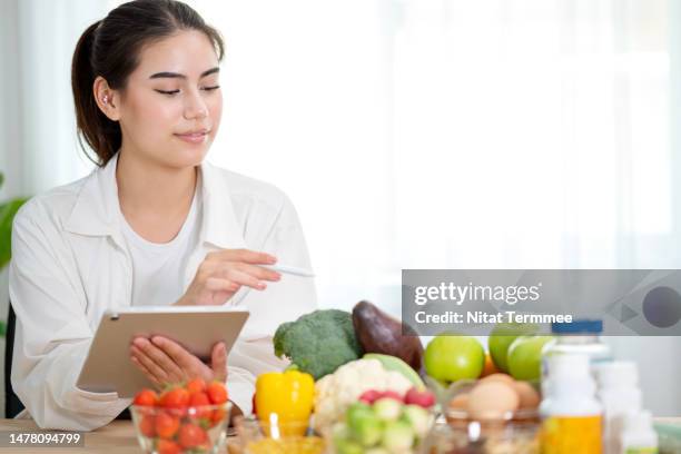 reduce your intake of sugar and processed foods to obesity prevent with nutrition planning. female nutritionists use a tablet computer to do weight loss plans for their customers via a mobile application. - data intake stock pictures, royalty-free photos & images