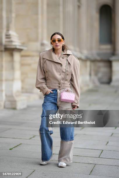 Gabriella Berdugo wears orange sunglasses from Moschino, gold and silver circle earrings, gold chain and pale green stones necklaces, a beige...