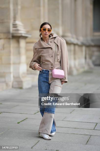 Gabriella Berdugo wears orange sunglasses from Moschino, gold and silver circle earrings, gold chain and pale green stones necklaces, a beige...