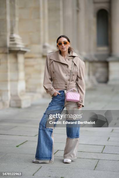 Gabriella Berdugo wears orange sunglasses from Moschino, gold and silver circle earrings, gold chain and pale green stones necklaces, a beige...