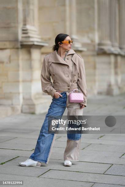 Gabriella Berdugo wears orange sunglasses from Moschino, gold and silver circle earrings, gold chain and pale green stones necklaces, a beige...