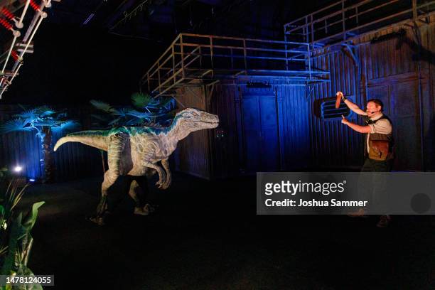 Museum guard interacts with a robot dinosaur at the "Jurassic World: The Exhibition" Press Preview at Odysseum on March 30, 2023 in Cologne, Germany.