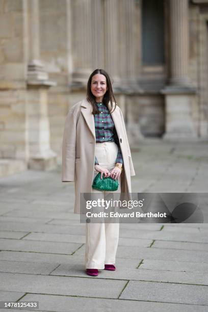 Alba Garavito Torre wears gold and green cross print pattern earrings, a green and purple checkered print pattern / puffy shoulder / buttoned shirt...