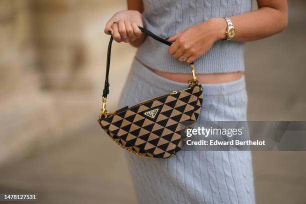 Gabriella Berdugo wears a silver pearls necklace, a green stones necklace, gold chains necklaces, a blue with black and white borders strap print...