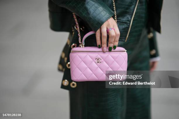 Gabriella Berdugo wears a pink plastic ring, a dark green shiny leather crocodile print pattern oversized zipper biker jacket, matching dark green...