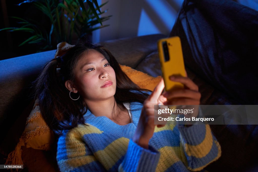 Asian girl using mobile phone, texting and surfing on social media.