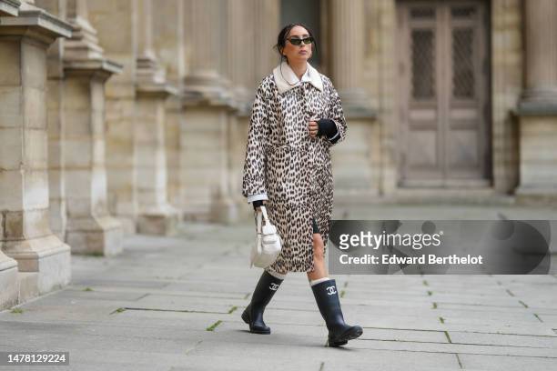 Gabriella Berdugo wears black cat eyes sunglasses, a white ripped cropped shirt from Saint Laurent Paris, a beige with black leopard print pattern...