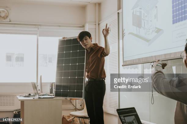 projet de travail de conception de regroupement, étudiant à la maîtrise aidant à présenter son travail de système de panneaux solaires devant la classe. - master class photos et images de collection