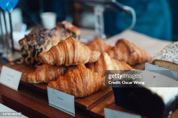 close-up of fresh croissants and loaf cake displaying on counter at bakery - auslage stock-fotos und bilder