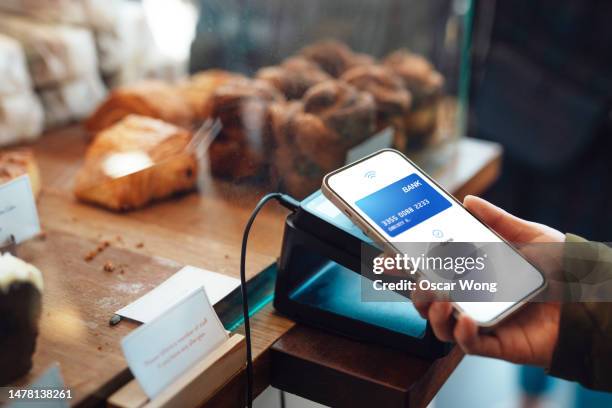 close-up of female hand making contactless payment with smartphone at cafe - apple pay mobile payment stock-fotos und bilder