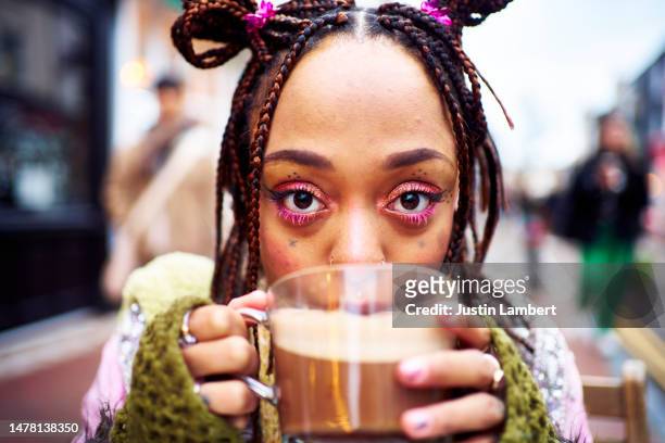 young woman enjoying a cup of hot chocolate looking to camera - lambert stock pictures, royalty-free photos & images
