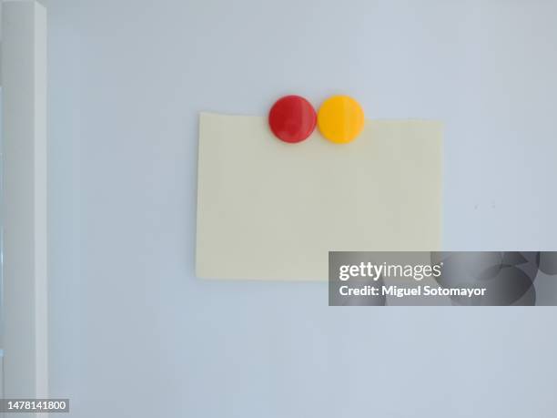 paper note attached to the fridge door with a magnet - magnete foto e immagini stock