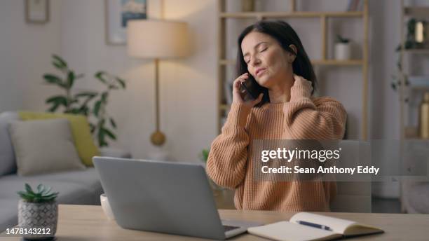 müde, remote-arbeit und eine frau mit nackenschmerzen bei einem telefonat mit burnout und terminstress. müdigkeit, verspätung und ein freiberuflicher mitarbeiter, der auf einem handy spricht, während er sich zurückreibt, um spannungen abzubauen - einzelne frau über 40 stock-fotos und bilder