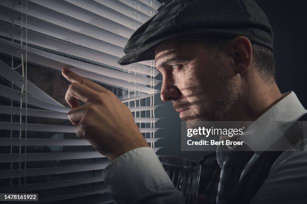 a man with a hat looking through the window - detektiv stock-fotos und bilder