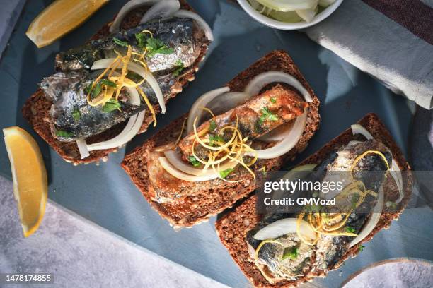 fischkonserven - sardinen mit zwiebeln und zitrone auf schwarzbrot - räucherfisch stock-fotos und bilder