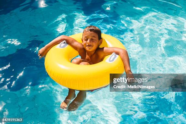 boy enjoys summer into the pool - float imagens e fotografias de stock