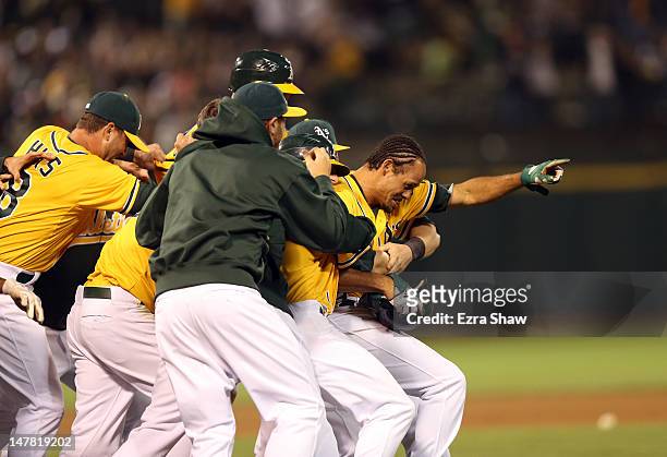 Coco Crisp of the Oakland Athletics is congratulated by teammates after he hit a sacrifice fly that scored Cliff Pennington to beat the Boston Red...