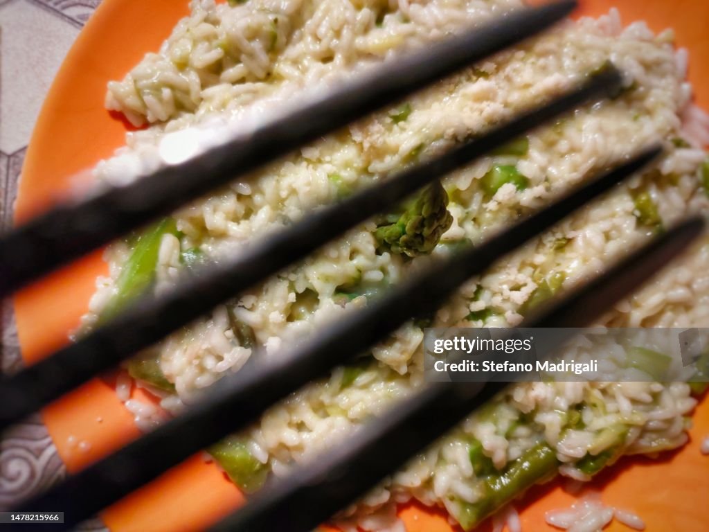 Dish with asparagus rice seen from above through the tip of a black fork