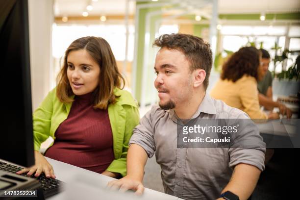 man helping his pregnant coworker at work - dwarf stockfoto's en -beelden