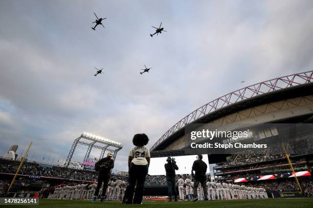 Boeing AH-64 Apache helicopters fly overhead during Opening Day before the game between the Seattle Mariners and the Cleveland Guardians at T-Mobile...