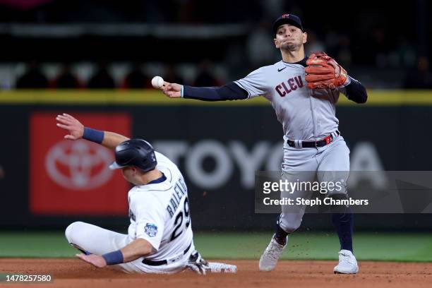 Andres Gimenez of the Cleveland Guardians turns a double play past Cal Raleigh of the Seattle Mariners during the fourth inning during Opening Day at...