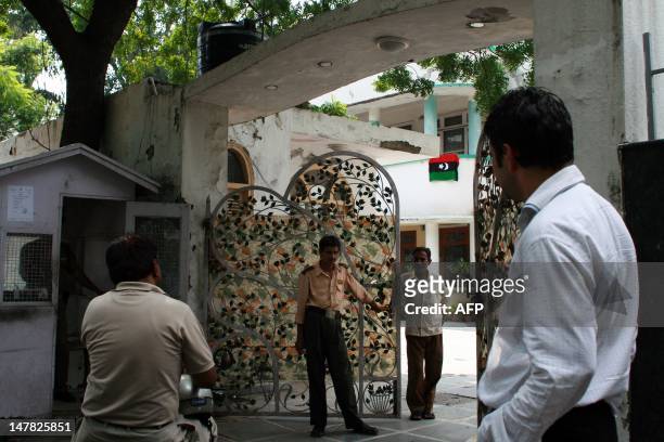 Libyan student and security staff stand outside the Libyan embassy in New Delhi on August 30, 2011 as the flag of the interim rebel government, the...