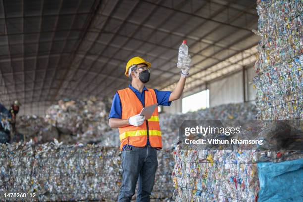 male worker examining plastic bottles at waste plant - abfallwirtschaft stock-fotos und bilder
