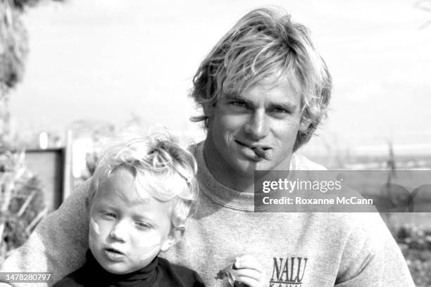 Surfer Laird Hamilton enjoys a snack with a child on Old Man's beach behind the scenes on the set of a commercial for Nike Aqua Socks in 1990 in San...