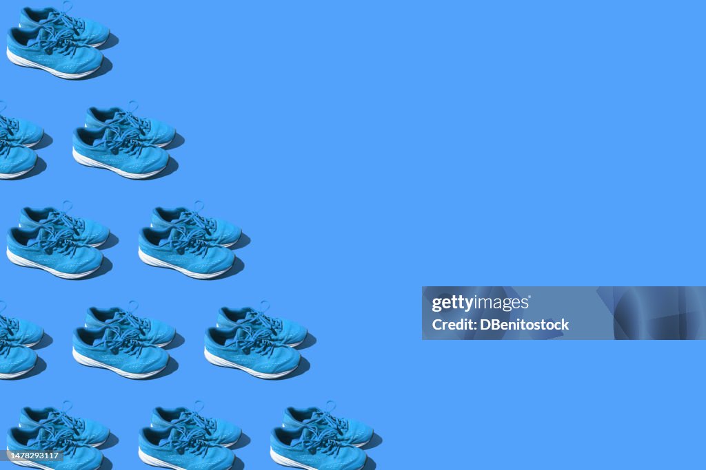 Pattern of used blue sneakers, on the left side, on a blue background. Concept of exercise, marathon, race, healthy life, training and comfort.
