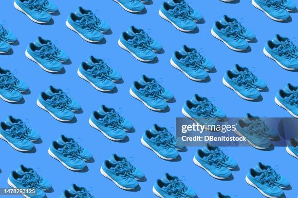 pattern of used blue sneakers on a blue background. concept of exercise, marathon, race, healthy life, training and comfort. - coaching formacion stock-fotos und bilder