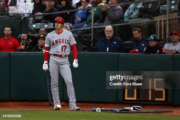 Shohei Ohtani of the Los Angeles Angels stands by the new pitch clock while standing in the on deck circle before batting against the Oakland...